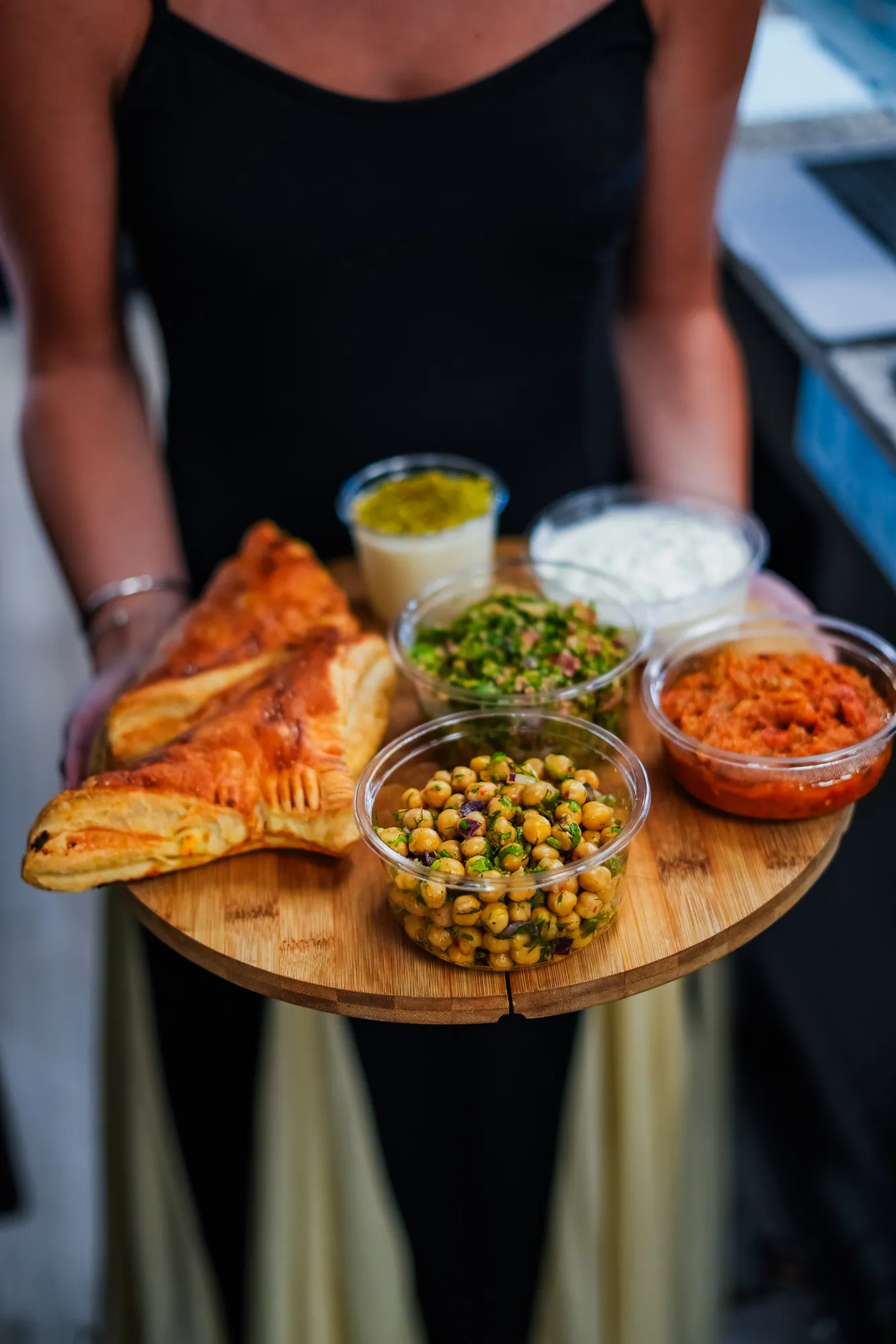 Plateau de mezzés tenu à la main : feuilletés, pois chiches, carottes et sauces